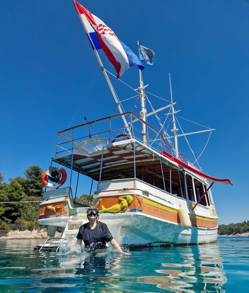 Traditional wooden Croatian excursion boat with flags in Bol